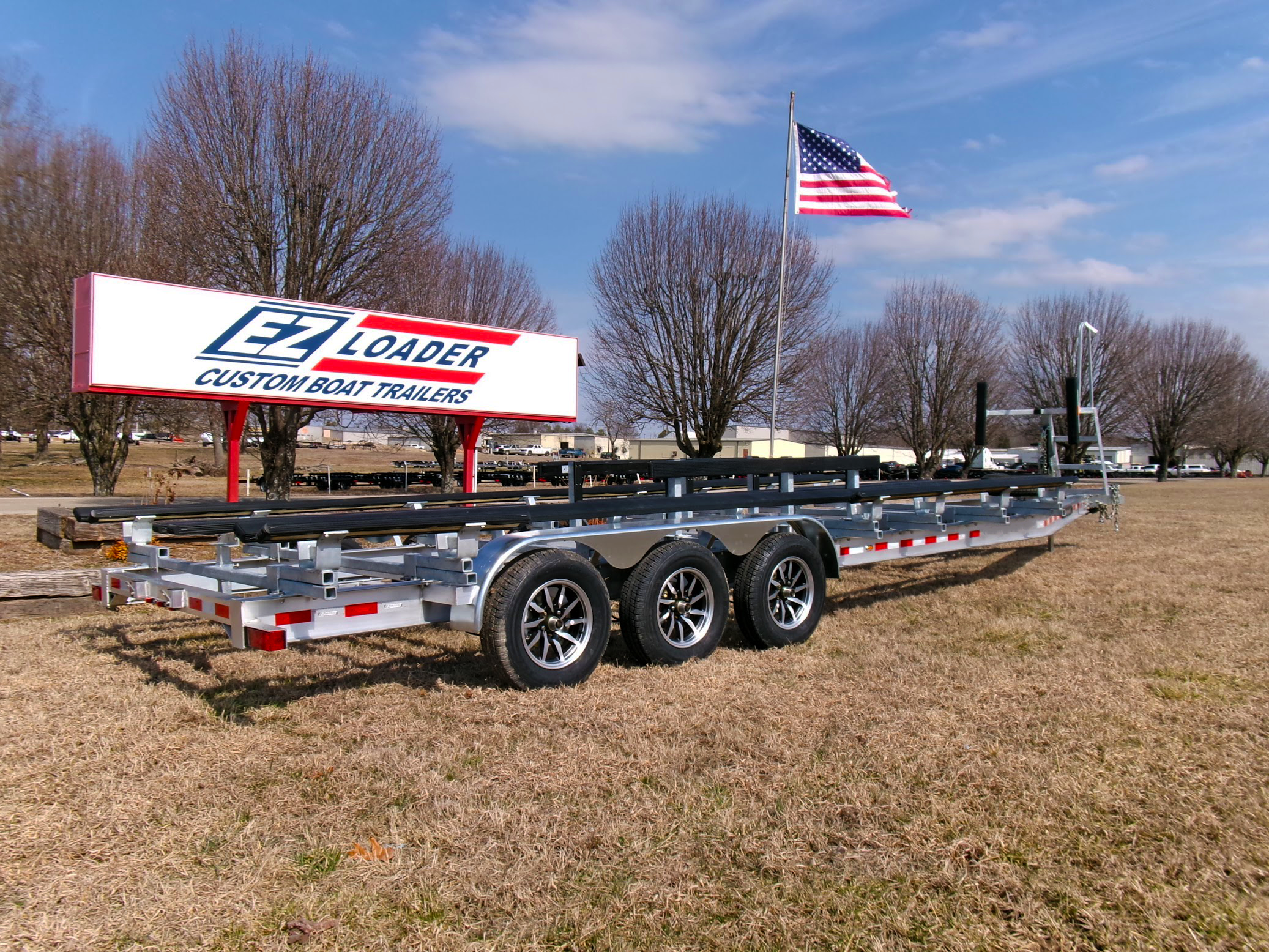 EZ Loader tandem axle black steel pontoon trailer with carpeted bunks, front boarding ladder, spare tire mount, and LED taillights