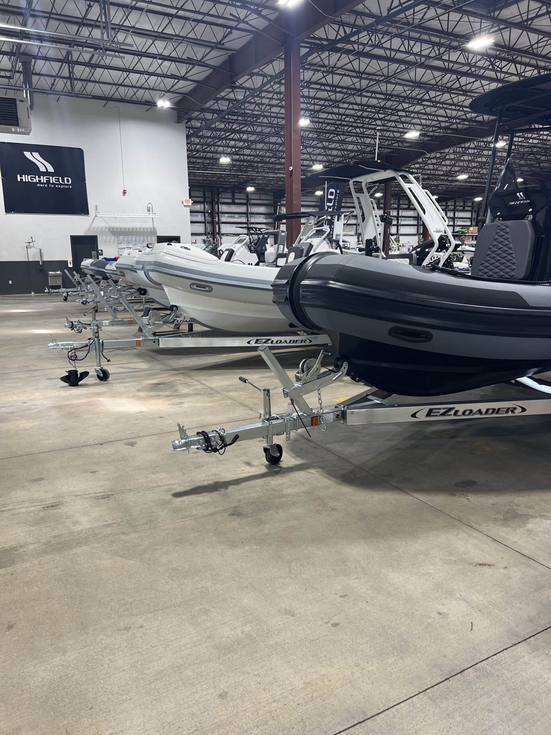 Green boat launching onto an EZ Loader boat trailer at a shallow waterfront.