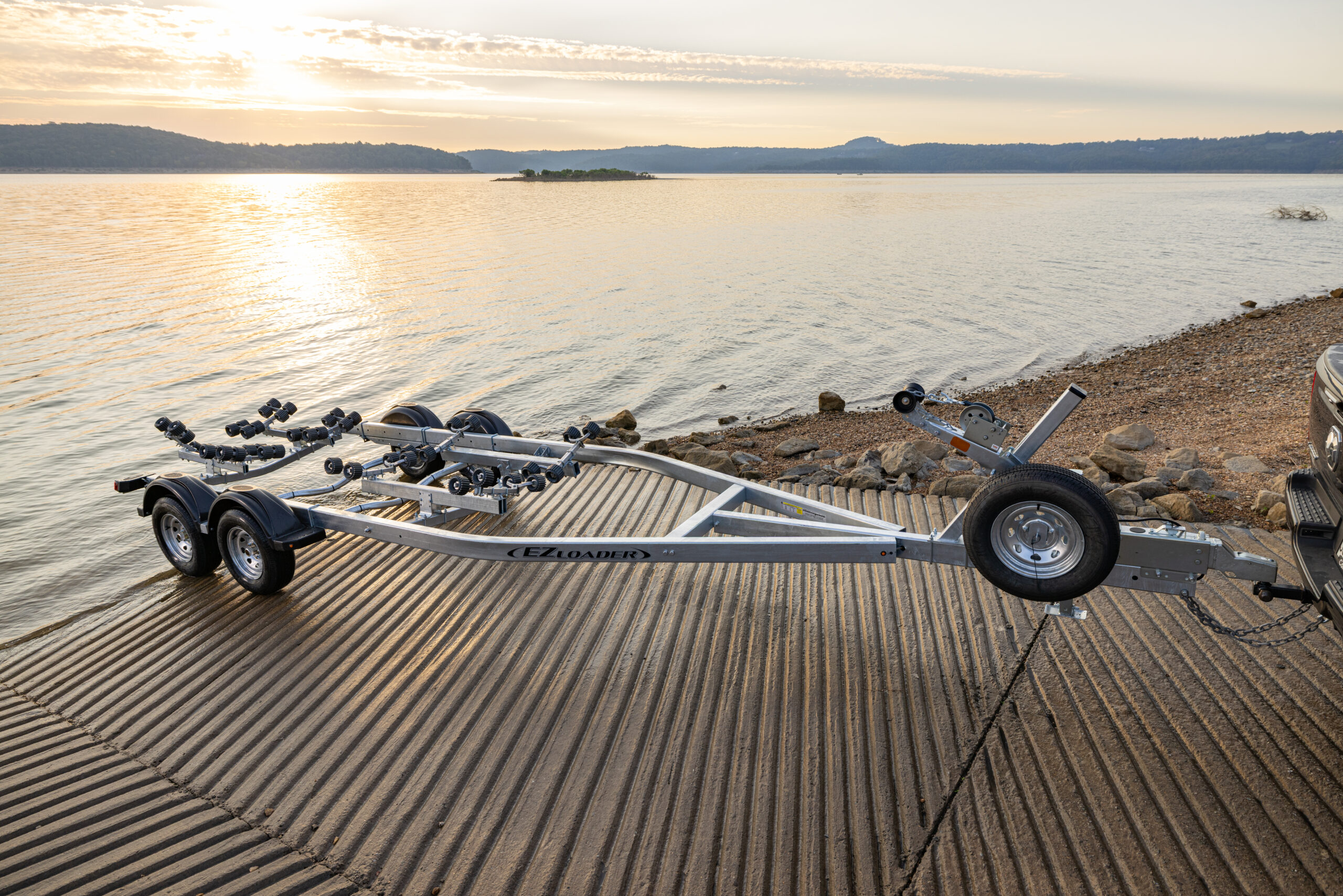 Tandem axle EZ Loader boat trailer with galvanized frame, multiple roller assemblies, alloy wheels, and extended winch post.