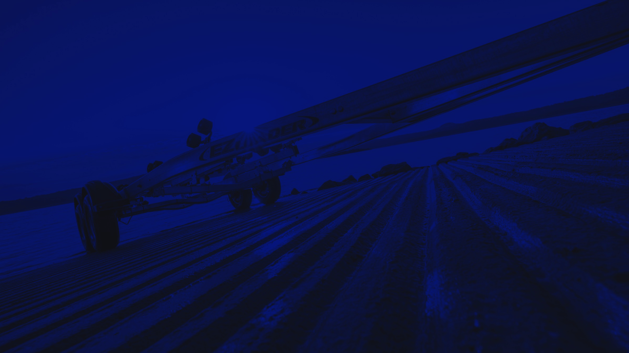 Tandem axle EZ Loader boat trailer with galvanized frame, multiple roller assemblies, alloy wheels, and extended winch post.