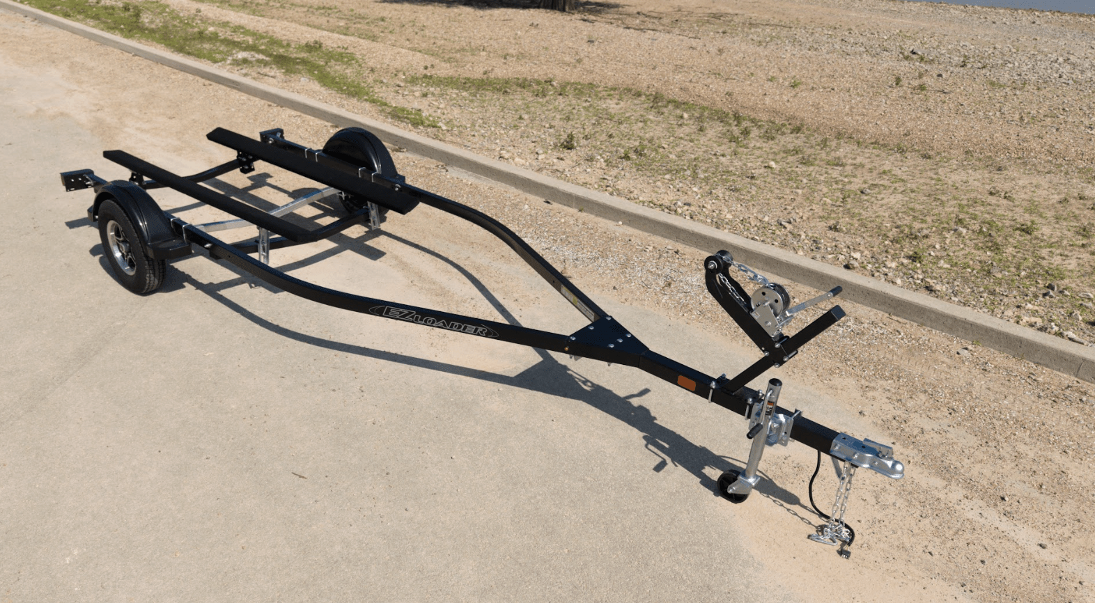 Tandem axle EZ Loader boat trailer with galvanized frame, multiple roller assemblies, alloy wheels, and extended winch post.