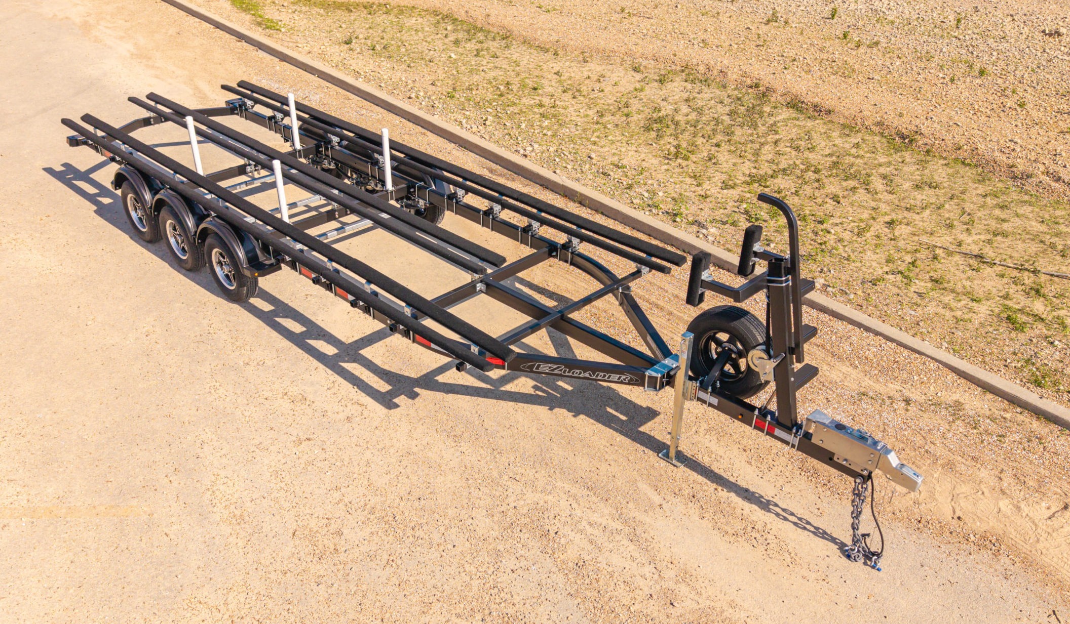Single axle black EZ Loader pontoon trailer with custom bunk supports and winch post, built for stable and efficient pontoon boat transport.