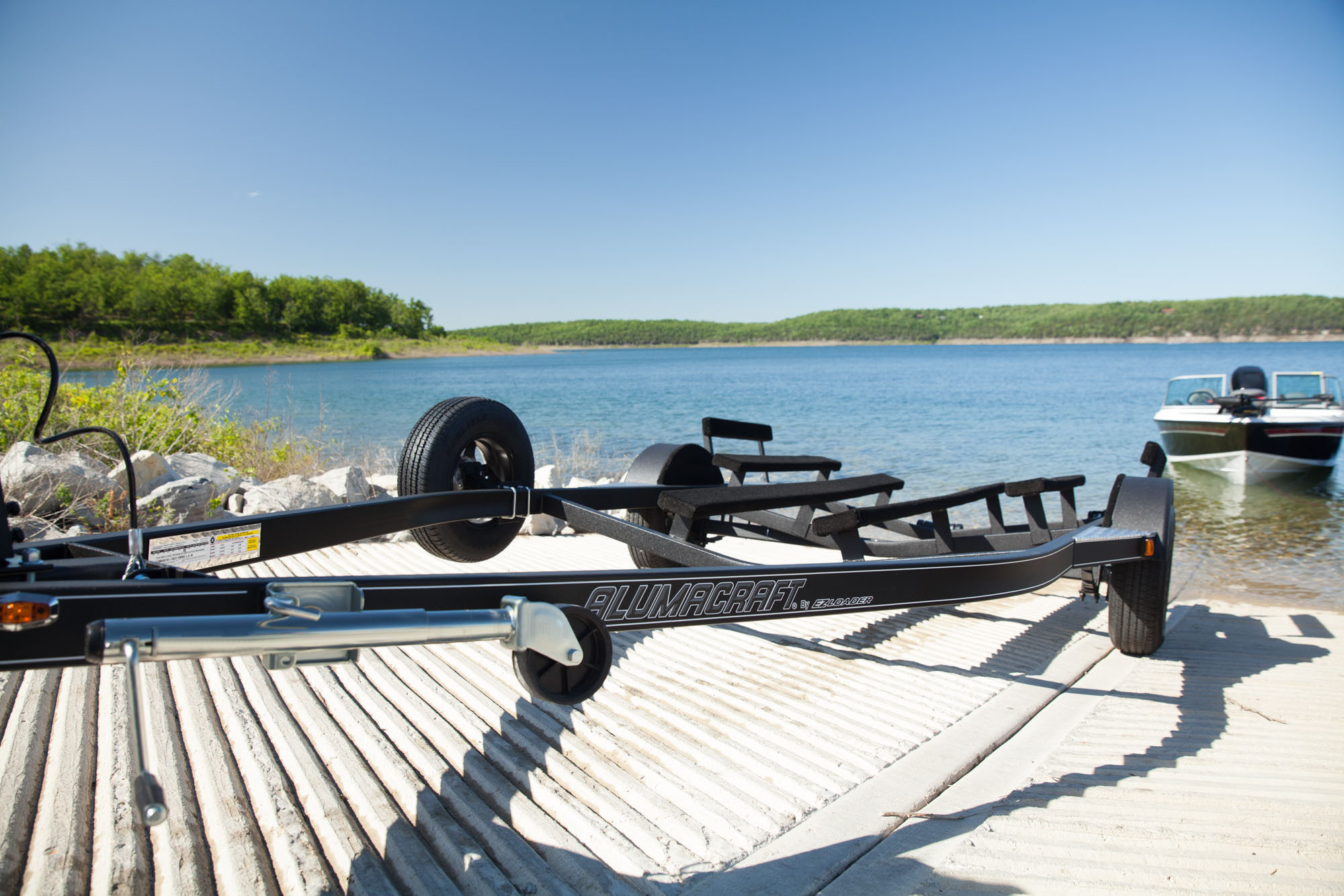 EZ Loader custom triple axle boat trailer with black powder-coated finish, diamond plate fenders, custom alloy wheels, and heavy-duty carpeted bunks designed for high-performance bass boats or tournament rigs.