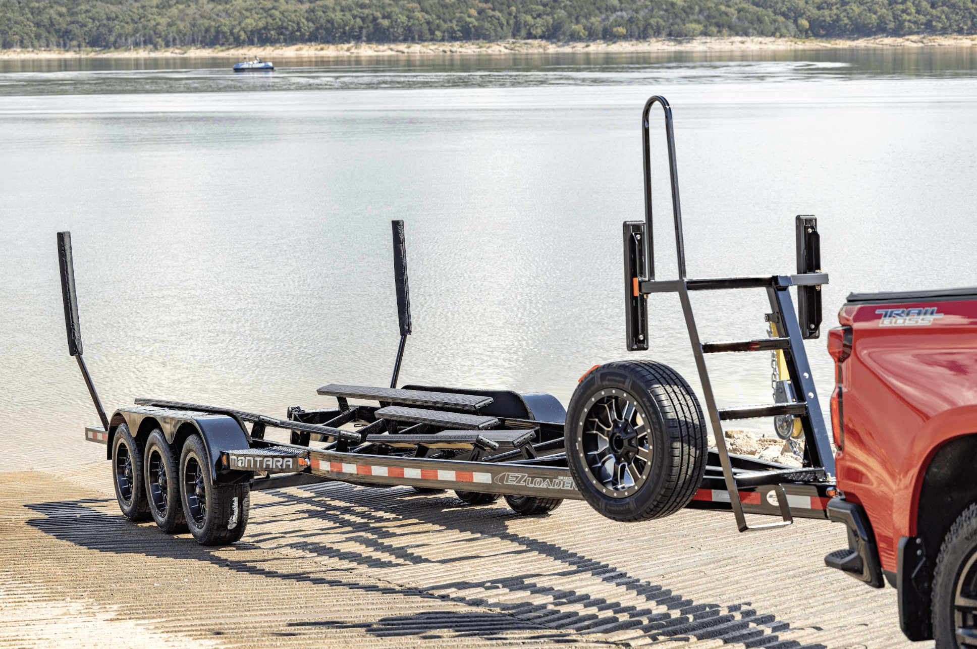 EZ Loader triple axle custom pontoon trailer with black powder-coated frame, heavy-duty bunk support system, integrated ladder winch stand, and premium aluminum wheels—built for hauling large pontoons with superior stability and style.