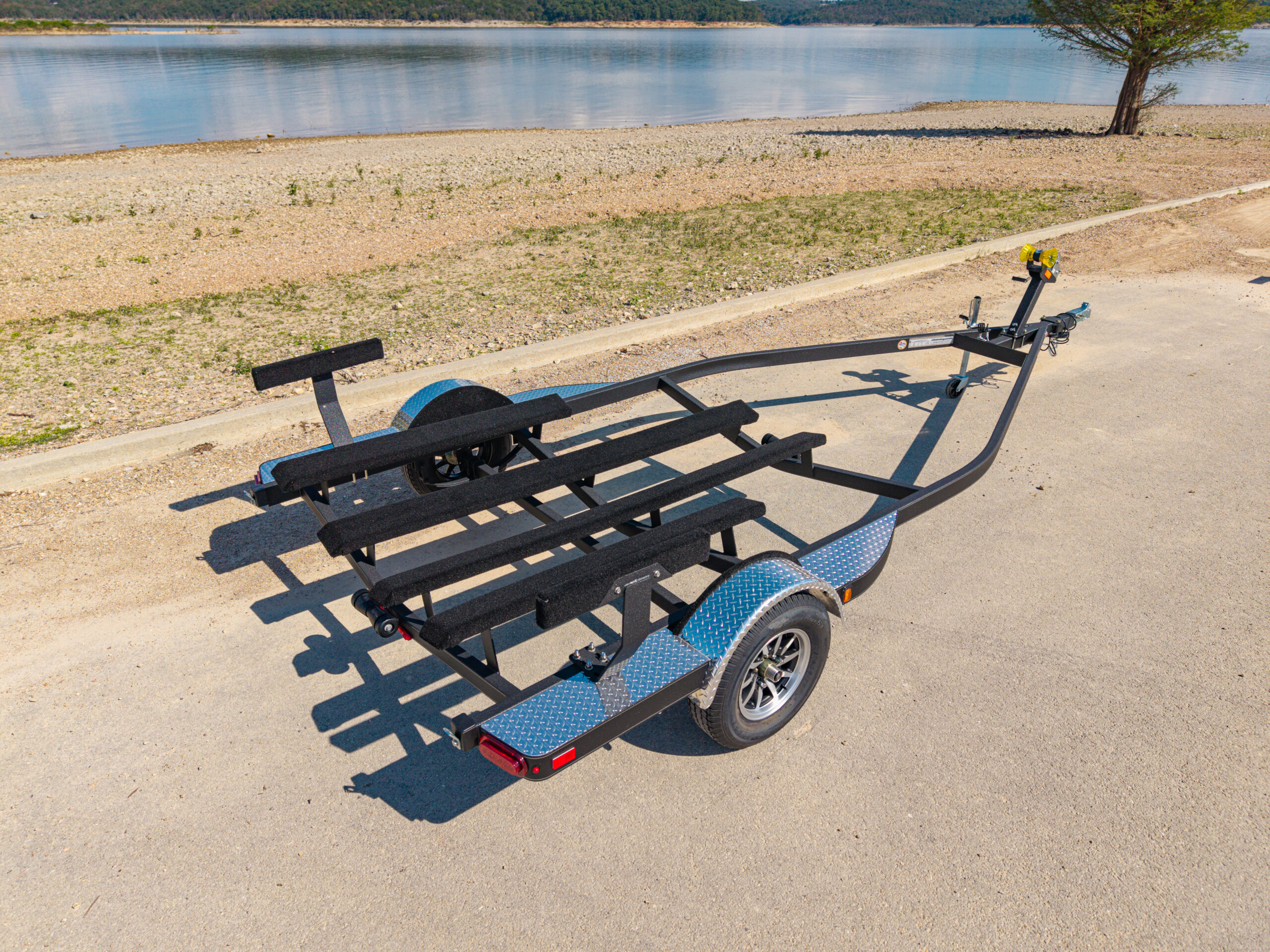 EZ Loader custom triple axle boat trailer with black powder-coated finish, diamond plate fenders, custom alloy wheels, and heavy-duty carpeted bunks designed for high-performance bass boats or tournament rigs.